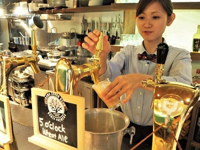 taste of okinawa　女性スタッフがグラスに生ビールを注いでいる
